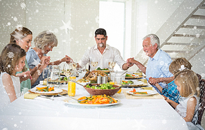 Composite image of family praying together before meal at dining table