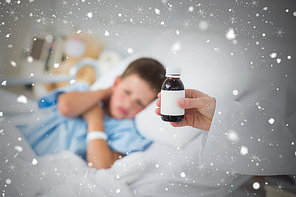 Doctor holding cough syrup with boy in hospital