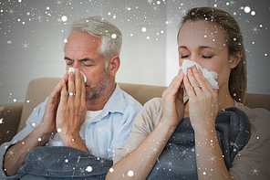 Composite image of sick couple blowing their noses sitting on the couch