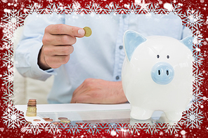 Mid section of a man putting some coins into a piggy bank