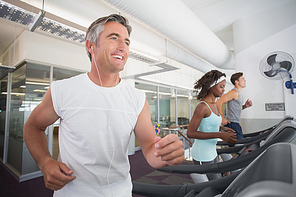 Fit man running on treadmill listening to music