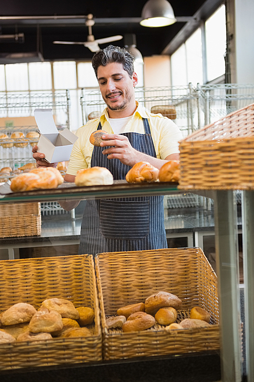 Smiling server holding bread and box at the bakery