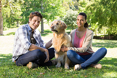 Happy couple with their dog in the park on a sunny day