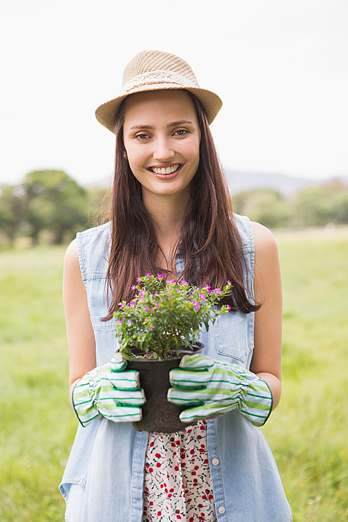 Happy woman holding potted flowers on a sunny day