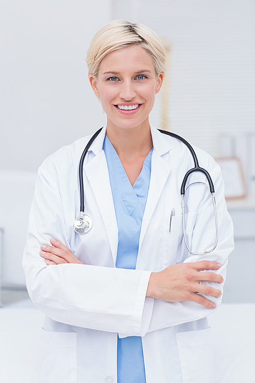 Portrait of confident female doctor with arms crossed standing in clinic