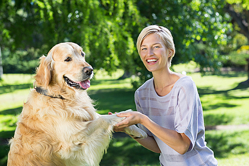 Happy blonde playing with her dog in the park on a sunny day