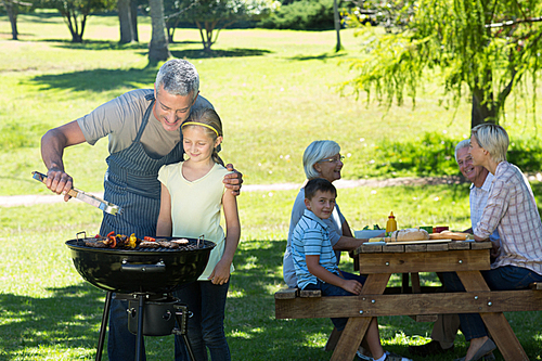 Happy father doing barbecue with his daughter on a sunny day