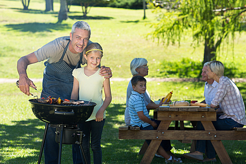 Happy father doing barbecue with his daughter on a sunny day