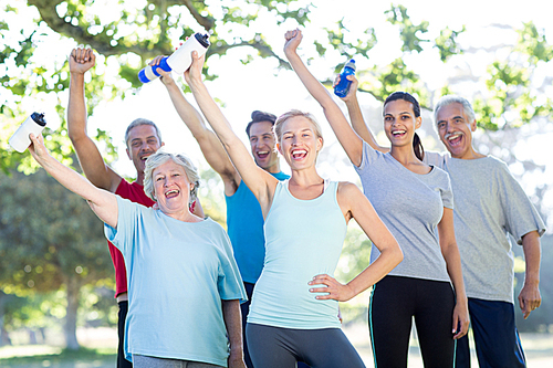 Happy athletic group holding up bottle of water on a sunny day