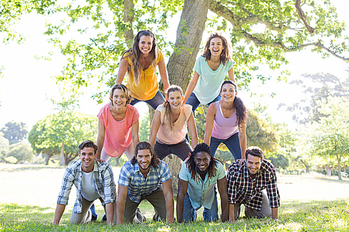 Happy friends in the park making human pyramid on a sunny day