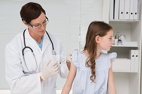 Doctor doing injection at a little girl in medical office