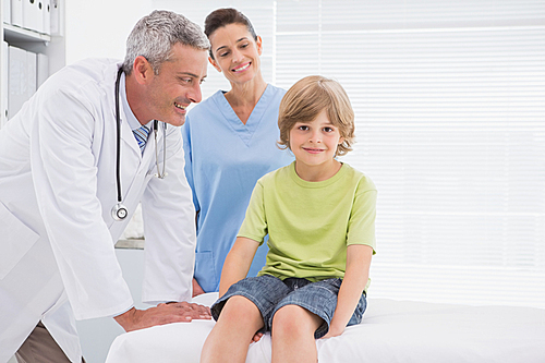 Little boy smiling at camera with doctors in medical office
