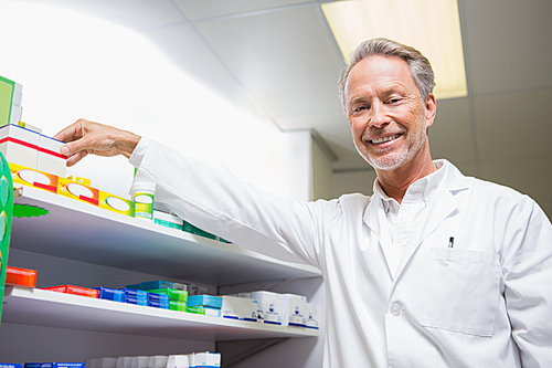 Senior pharmacist taking medicine from shelf in the pharmacy