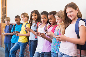 Cute pupils using mobile phone at the elementary school