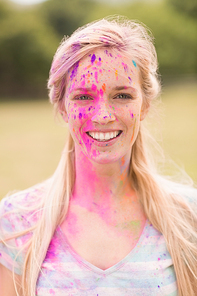 Happy blonde covered in powder paint on a sunny day