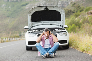 Stressed man sitting after a car breakdown at the side of the road