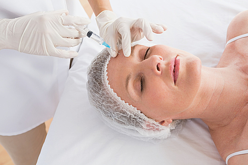 Woman receiving botox injection on her forehead in medical office