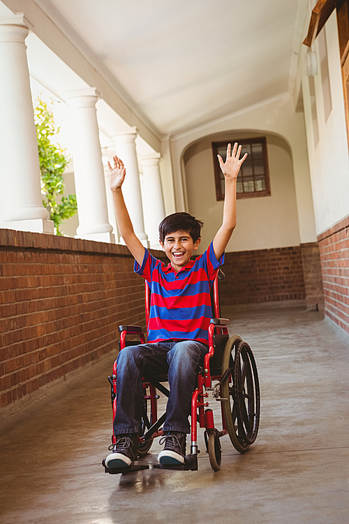 Portrait of cute little boy in wheelchair in school corridor
