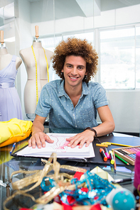 Portrait of attractive male fashion designer sketching at table