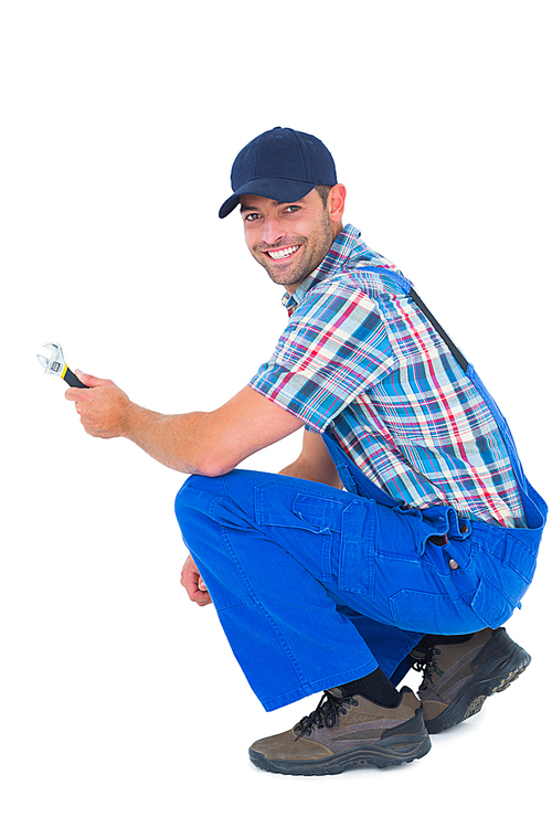 Full length portrait of happy handyman holding wrench on white background