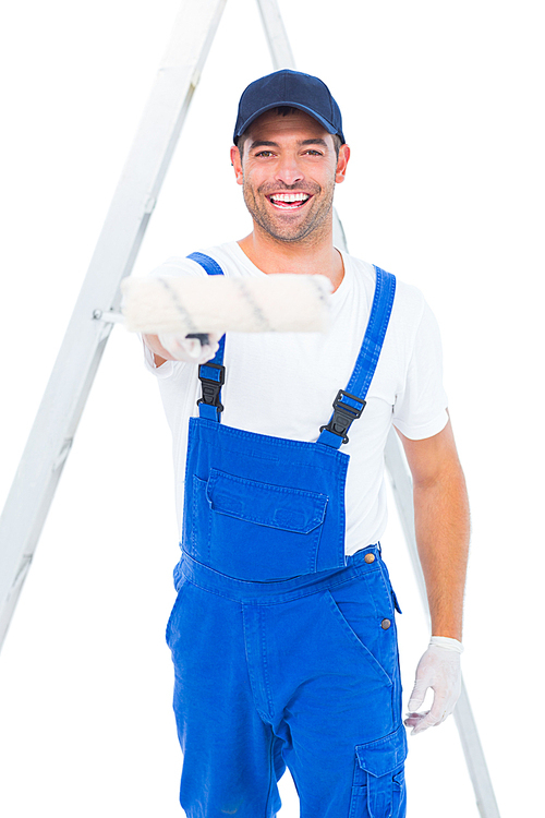 Portrait of smiling handyman using paint roller on white background