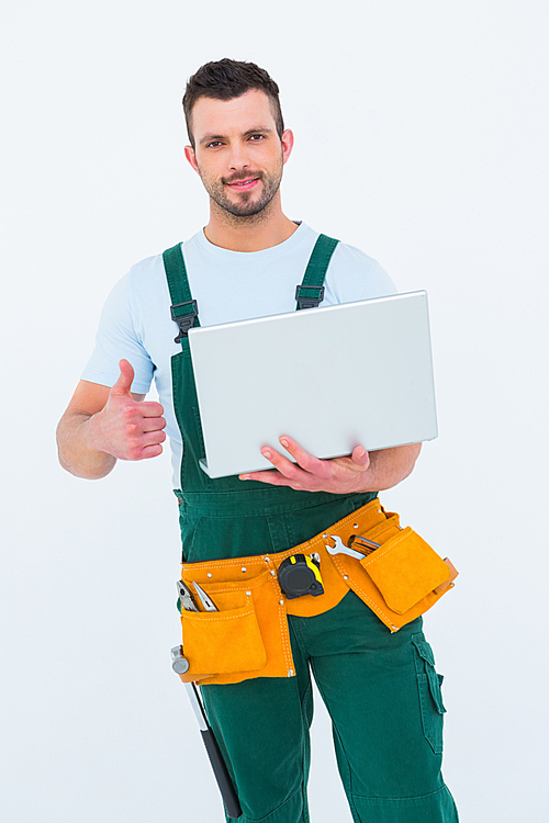 Smiling construction worker holding laptop on white backboard