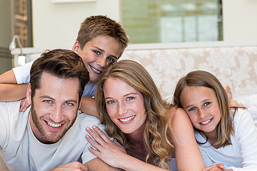 Happy family smiling at camera at home in bedroom