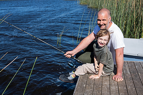 Happy man fishing with his son in the countryside