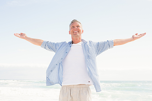 Handsome man with arms outstretched at the beach