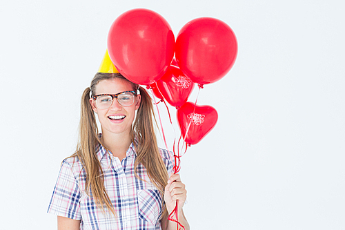 Geeky hipster smiling at camera and holding red balloons on white background