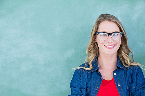 Smiling geeky teacher standing in front of blackboard in classroom
