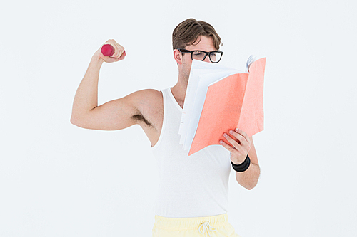 Geeky hipster lifting dumbbells and reading notepad on white background