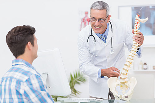 Doctor explaining a spine model to patient in medical office