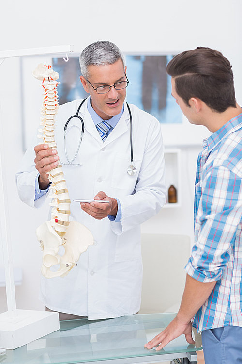 Doctor explaining the spine to his patient in medical office