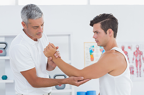 Doctor examining his patient arm in medical office