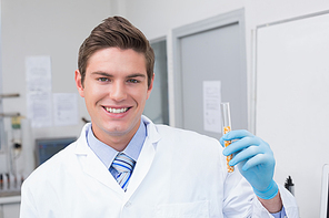 Smiling scientist holding test tube with corn inside