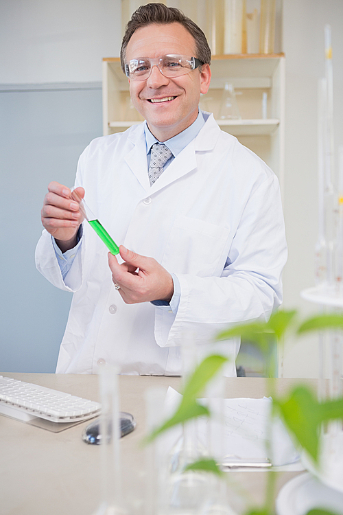 Scientist smiling at camera holding tube