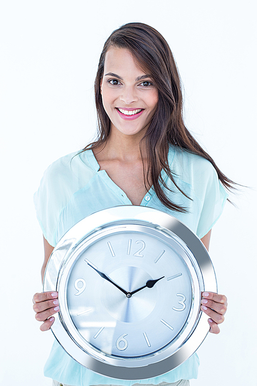 Pretty brunette holding a clock smiling at camera