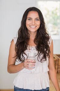 Pretty brunette drinking glass of water in the kitchen