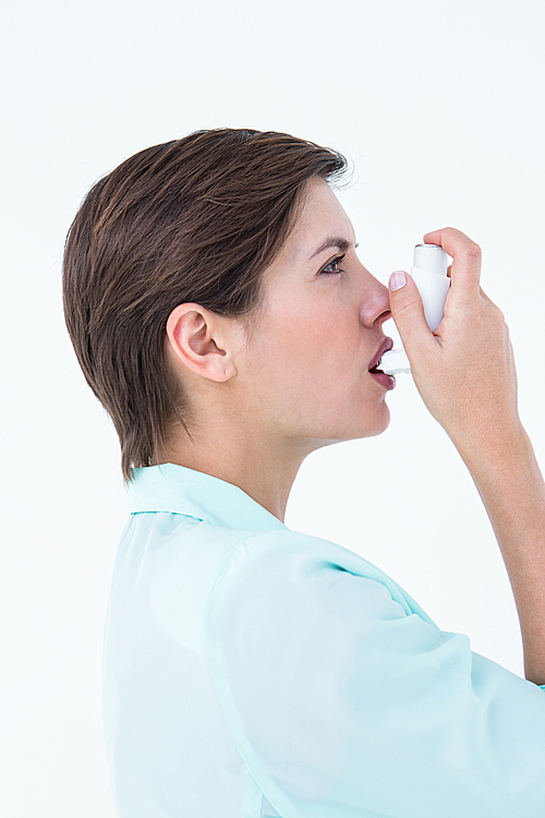Pretty woman using her inhaler on white background