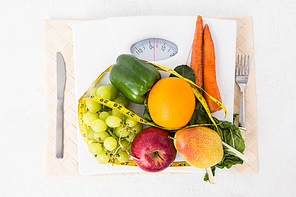 Weighing scales with fruits and vegetables on white background
