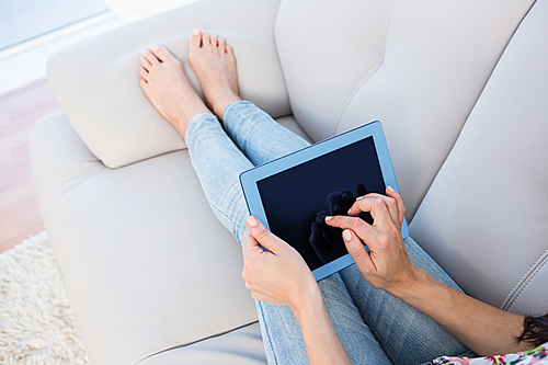 Woman using tablet computer on couch at home in the living room