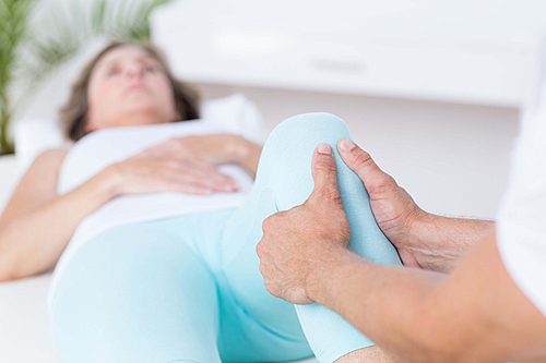 Physiotherapist doing leg massage to his patient in medical office