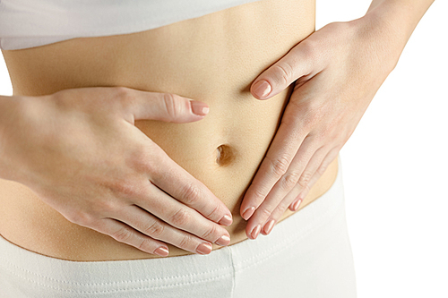 Slim woman touching her belly on white background
