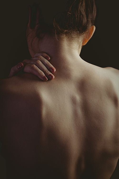 Nude woman with a shoulder injury on black background