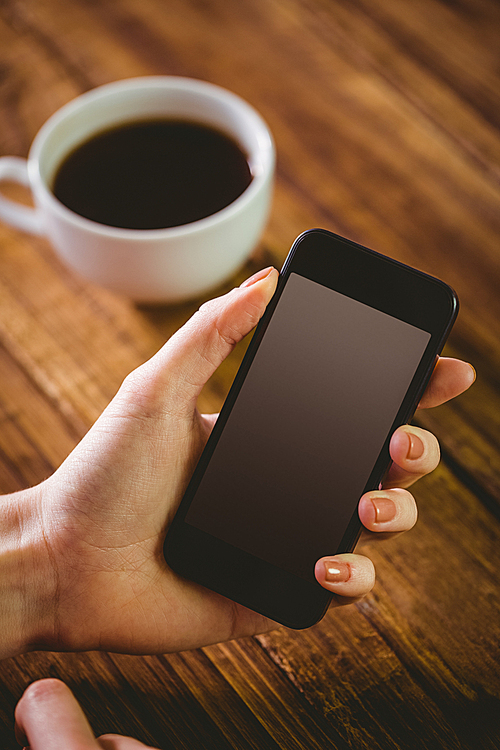 Woman using her smartphone on wooden table