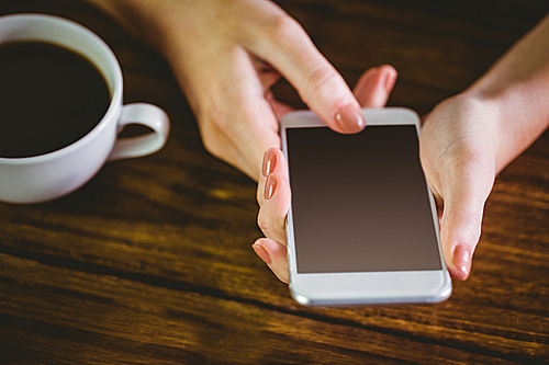 Woman using her smartphone on wooden table