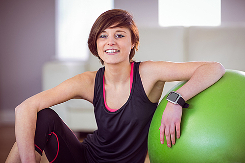 Fit woman sitting next to exercise ball at home in the living room