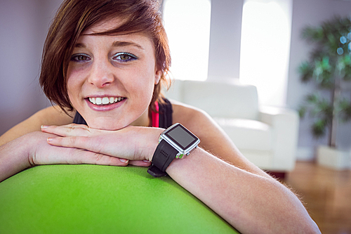 Fit woman leaning on exercise ball at home in the living room