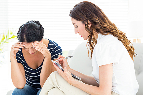 Therapist listening her patient and taking notes on white background